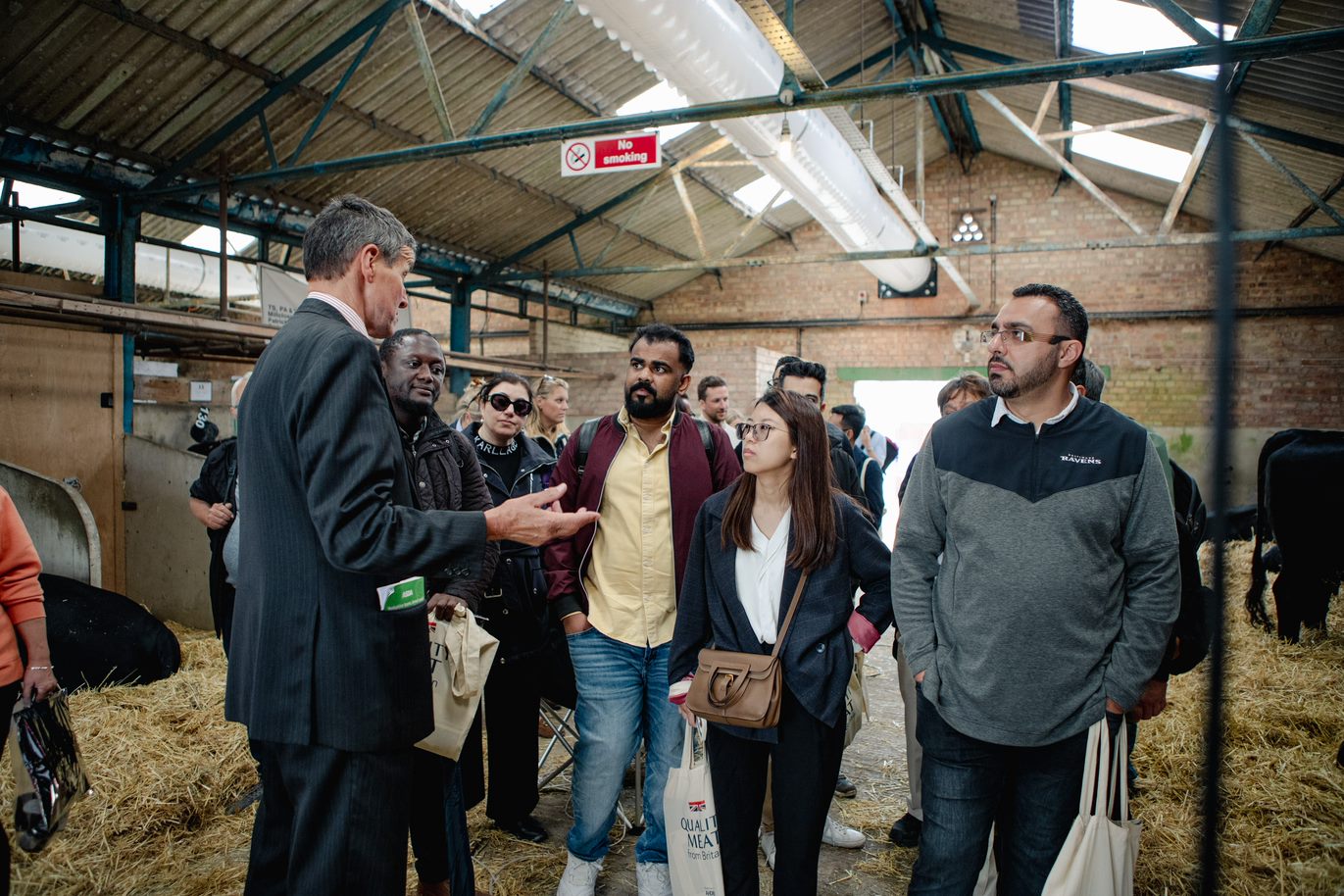 Group of people being shown around a cow shed on farm